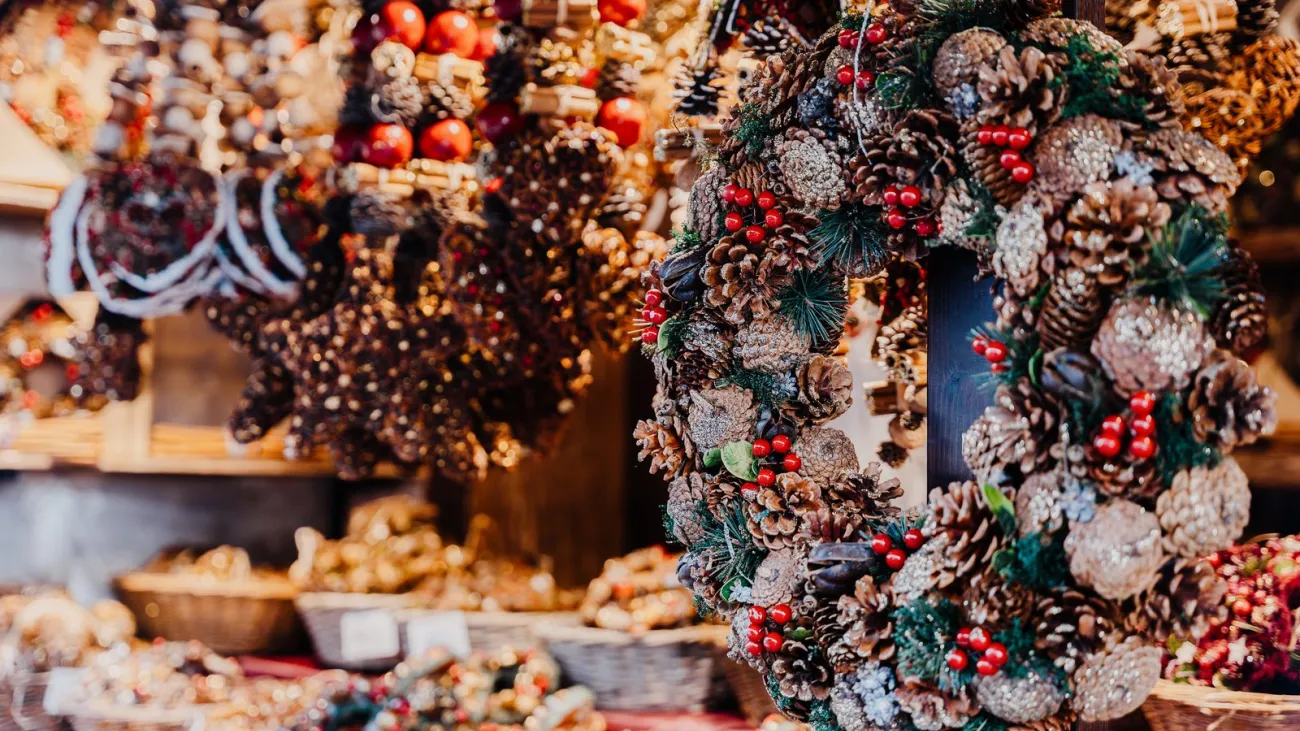Handmade pinecone wreaths with red berries on a holiday market stall