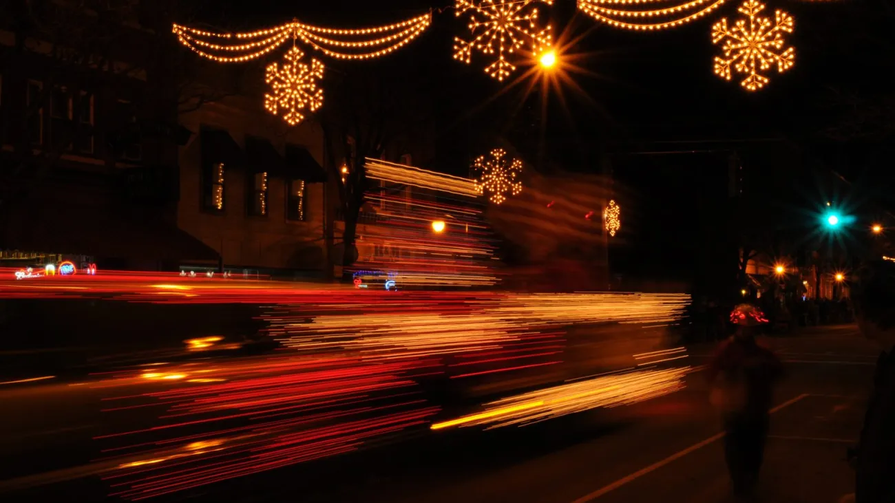Christmas lights and streaks of light from a night parade on a town street