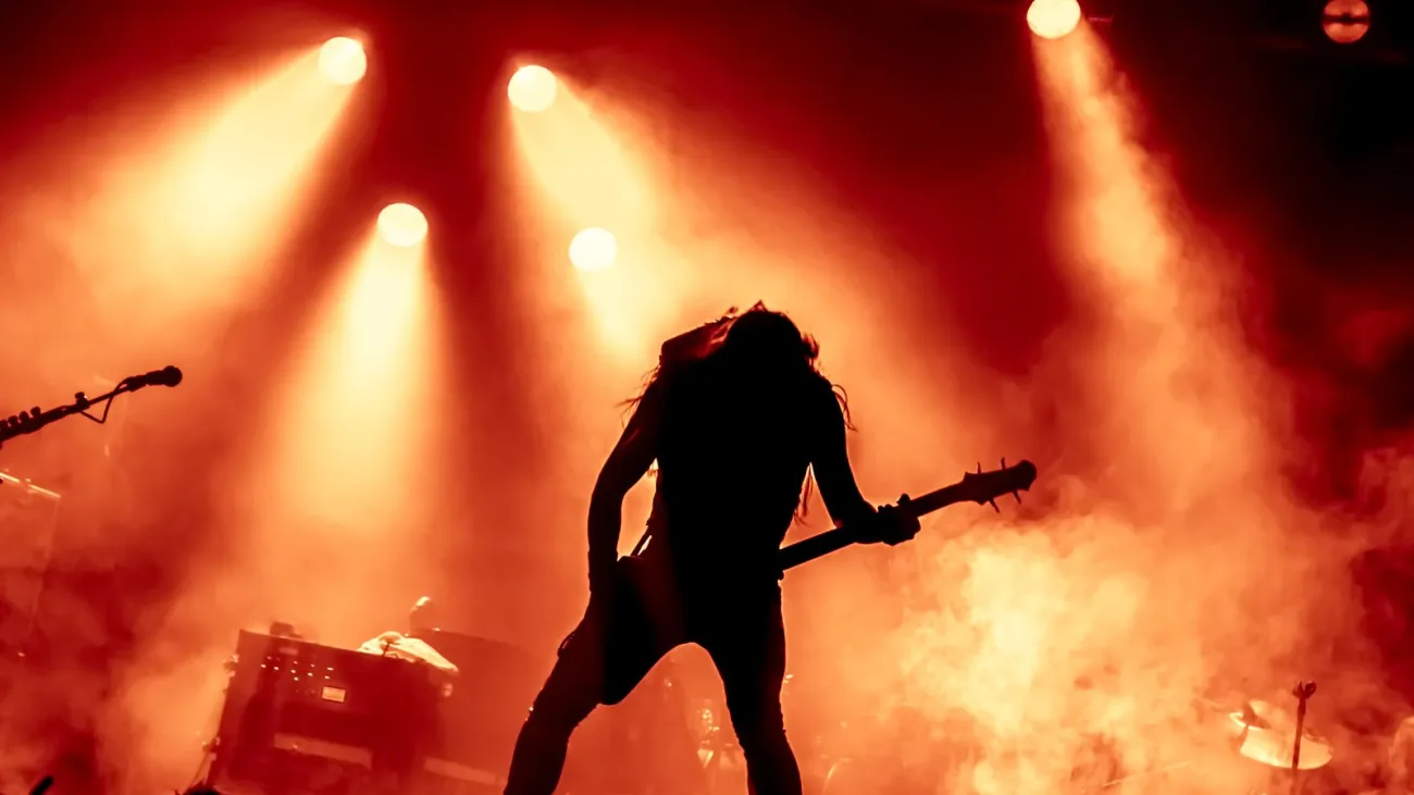 Silhouette of guitar player in action on stage in front of concert crowd