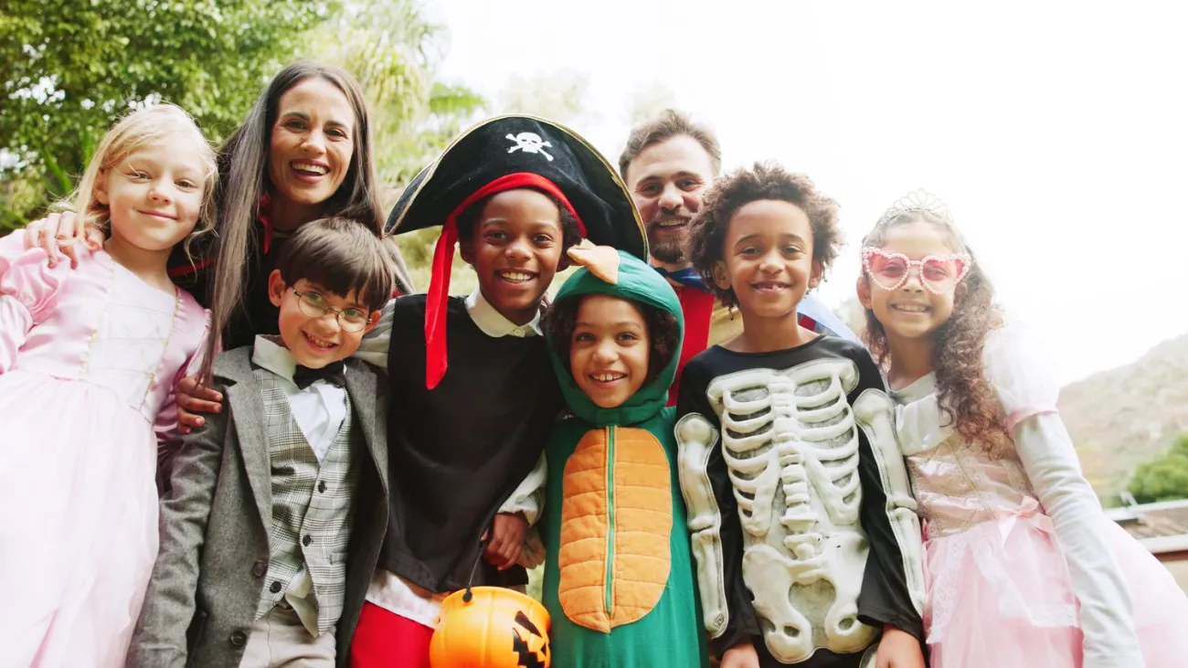 Parents and kids in costumes celebrating Halloween outdoors