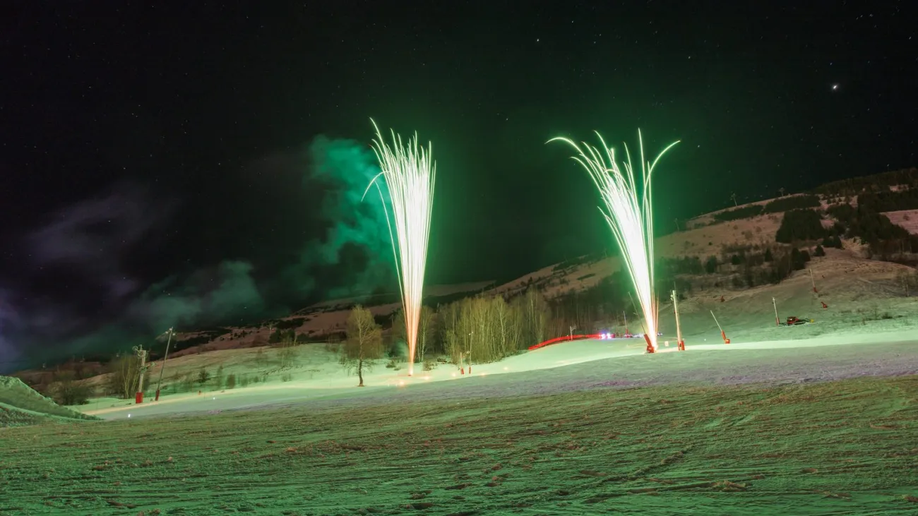 Fireworks over a snowy ski slope at night