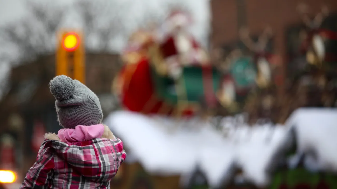 Girl on her father's shoulders watching Santa at a parade