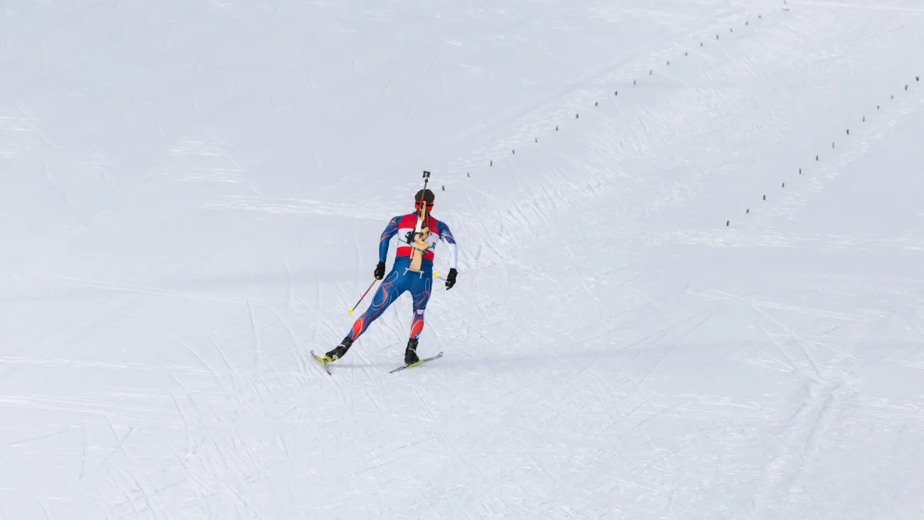 Biathlete skiing with a rifle on his back