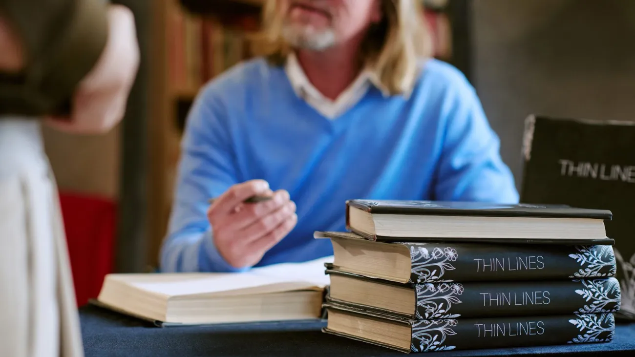 Author seated at a table signing books