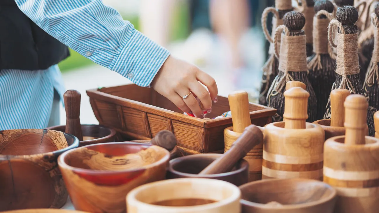 Shopper reaching into a handmade wooden bowl at a craft fair
