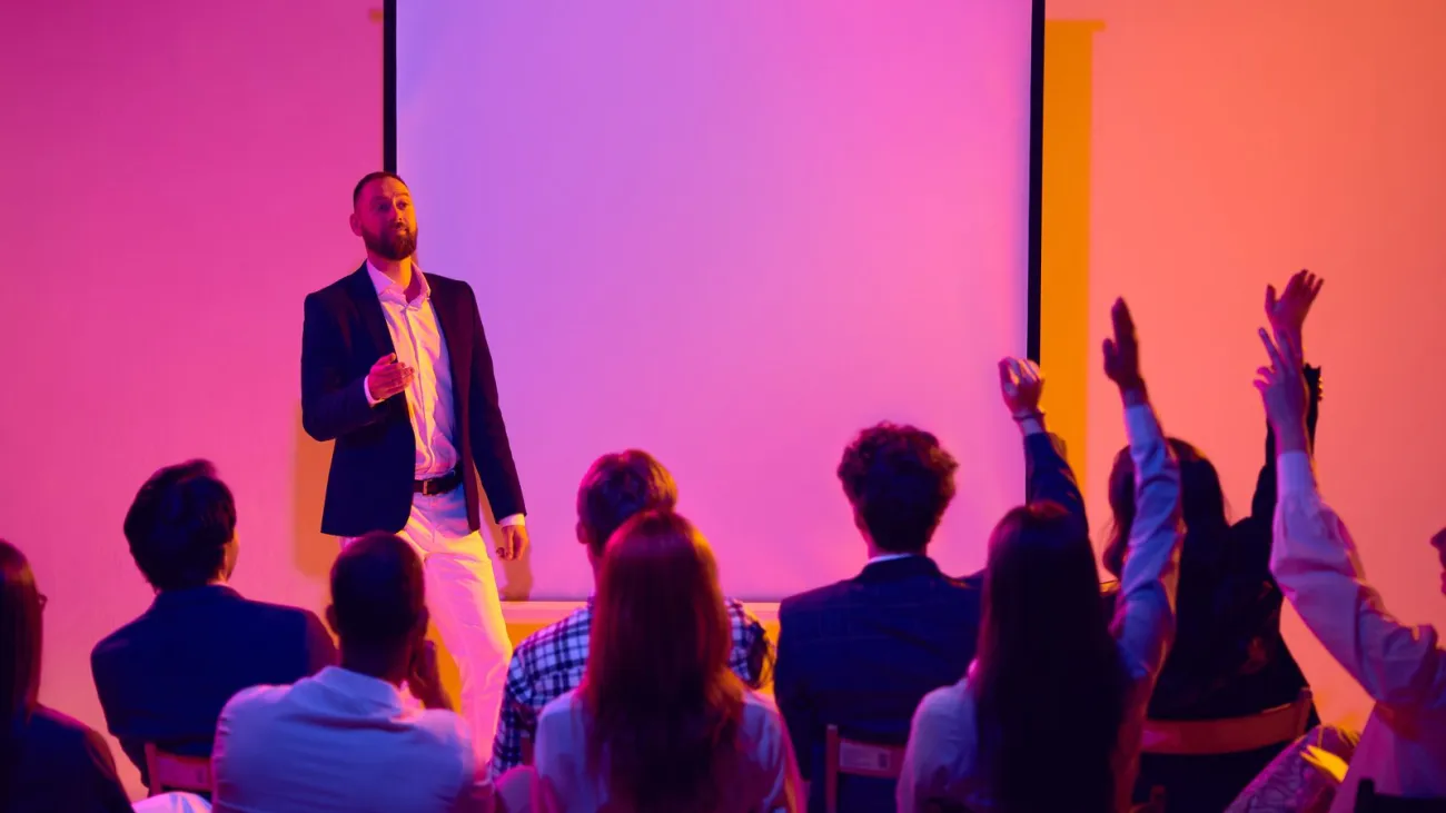 Speaker answering audience questions beside a screen