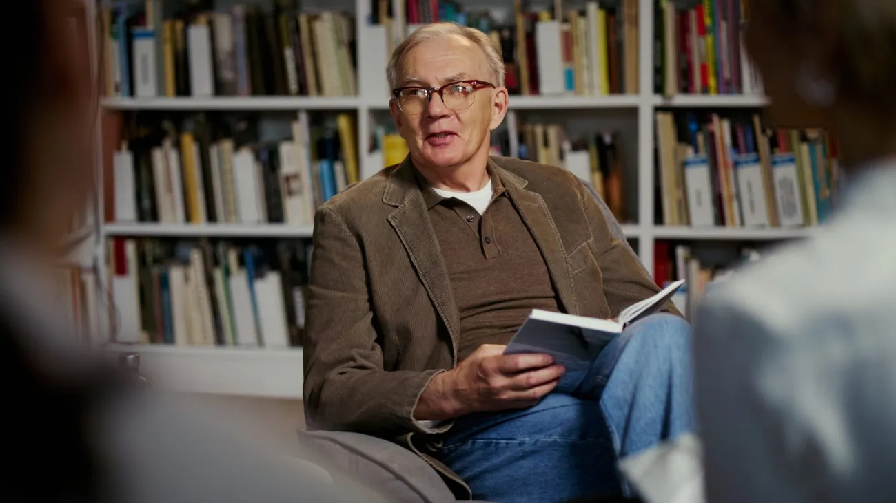Man reading aloud from a book to a group