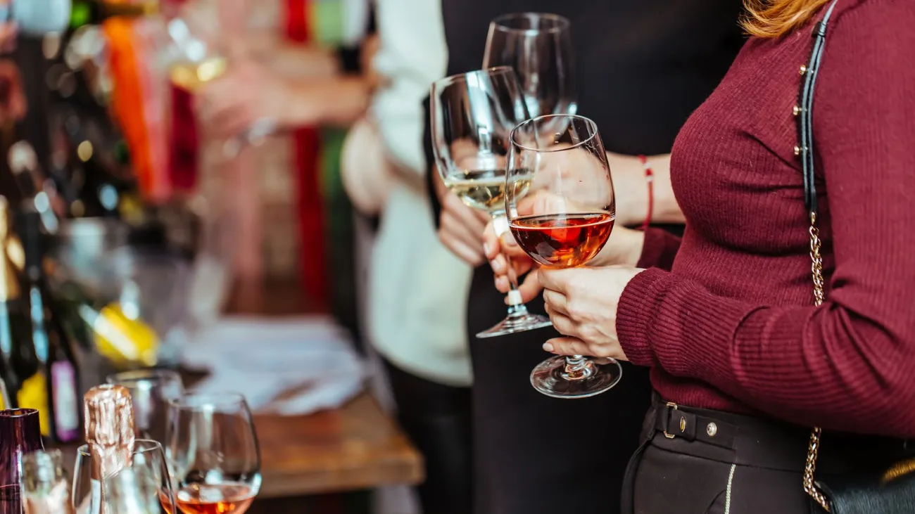 Visitors holding glasses of wine at a tasting table