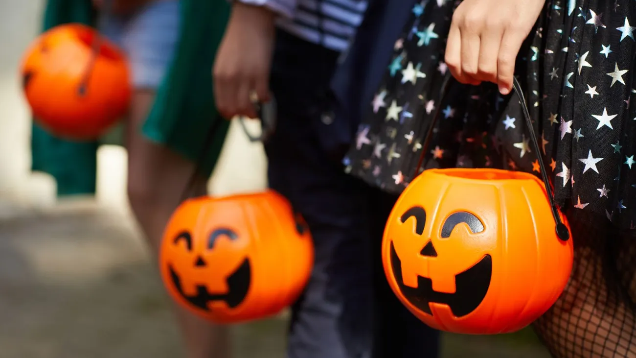 Children holding pumpkin candy bags while trick or treating