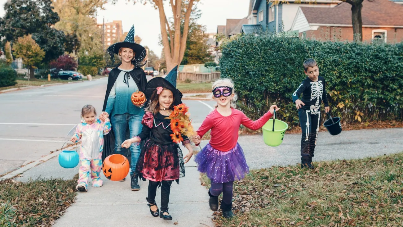 Mother and children in costumes going trick or treating