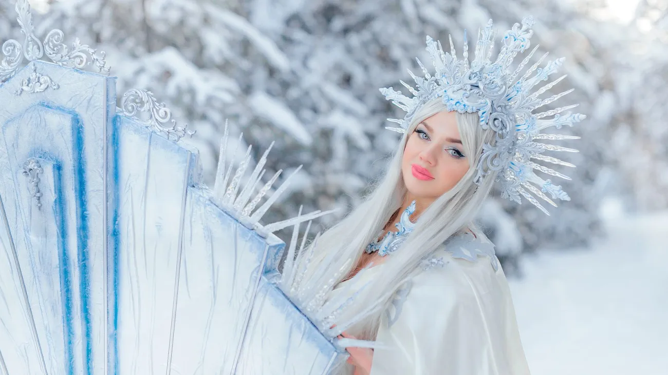 Young girl dressed as a snow queen in a winter forest