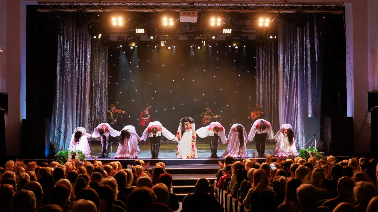 A collective of musicians, singers and dancers in gypsy costumes perform on stage
