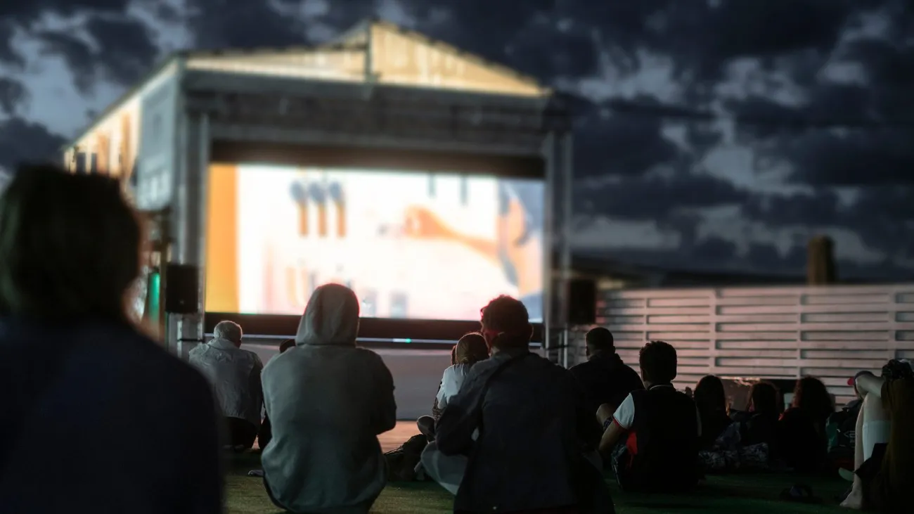 Crowd of people watching a movie in the open air cinema at night