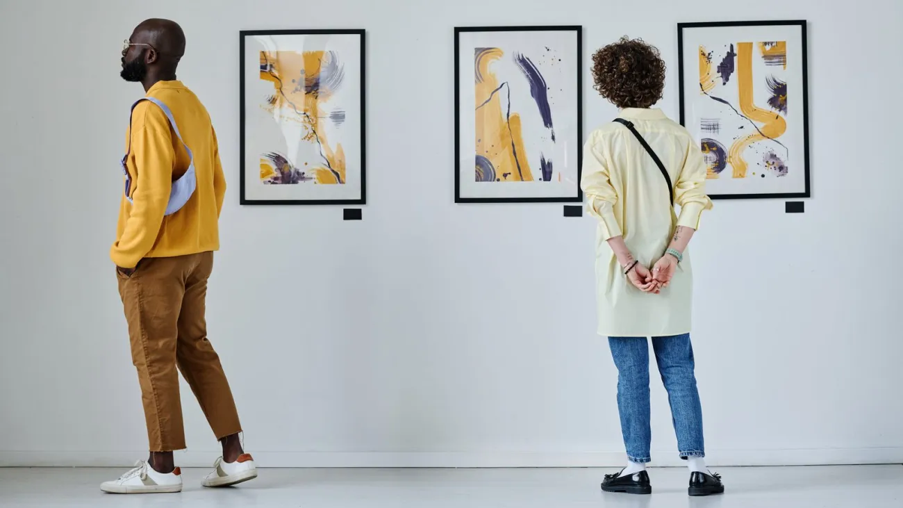 Visitors looking at paintings on a gallery wall