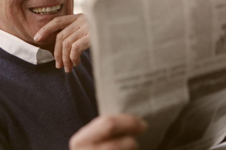 Man holding newspaper smiling