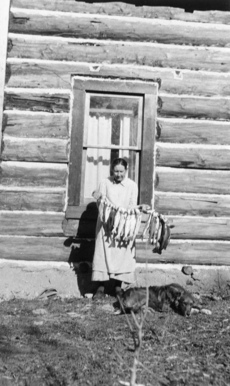 Josephine Doody with a catch of fish, in front of homestead cabin, Nyack. ca 1910s Courtesy of the Glacier National Park Archives (Medium)