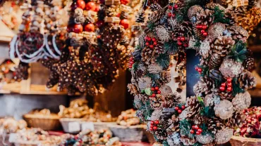 Handmade pinecone wreaths with red berries on a holiday market stall