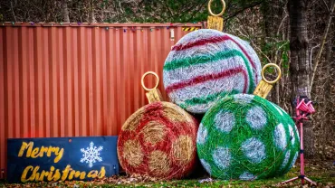 Big round hay bales painted as Christmas ornaments on a rural lot