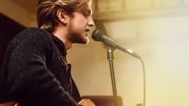Bearded singer performing a song on stage