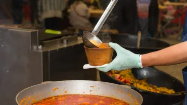 Ladling soup from a large pot into a bowl
