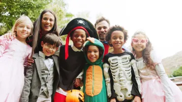 Parents and kids in costumes celebrating Halloween outdoors