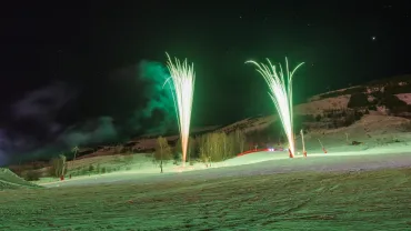 Fireworks over a snowy ski slope at night