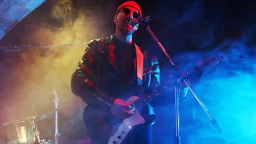 Man playing electric guitar on a smoky stage