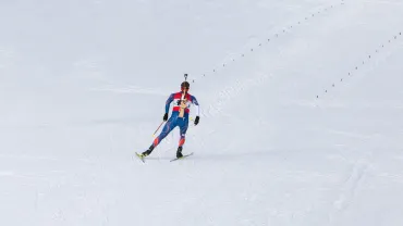 Biathlete skiing with a rifle on his back