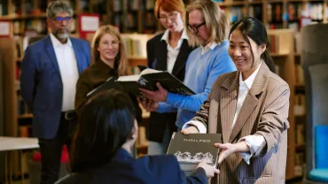 Reader handing a book to an author at a signing