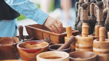 Shopper reaching into a handmade wooden bowl at a craft fair