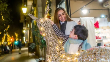 Mother and son enjoying Christmas lights on a downtown street