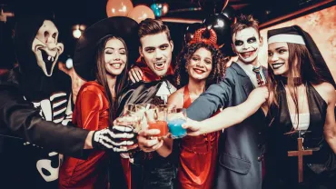 Friends in Halloween Costumes Drinking Cocktails