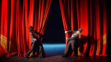Actors in costume behind a theater curtain