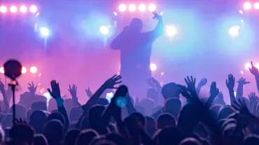 Concert, silhouettes of happy people raising up hands, Music show. Bright scene lighting in club. Fans burn red flares a