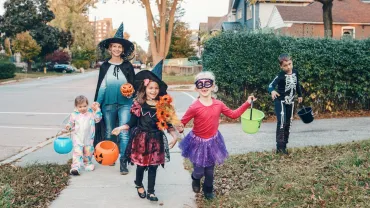 Mother and children in costumes going trick or treating