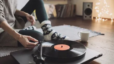 Young woman listening to music, relaxing, enjoying life at home. Girl wearing warm winter clothes having fun. Turntable