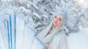 Young girl dressed as a snow queen in a winter forest