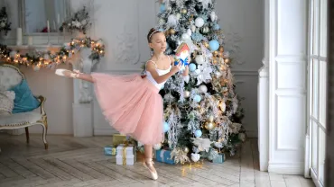 Young ballerina on pointe near a Christmas tree