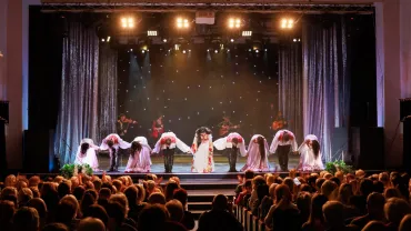 A collective of musicians, singers and dancers in gypsy costumes perform on stage