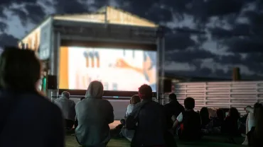 Crowd of people watching a movie in the open air cinema at night