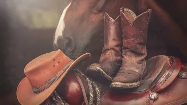 Cowboy hat and worn boots on a western saddle