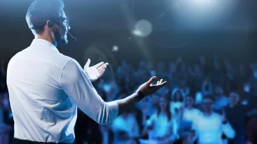 Speaker with a headset microphone giving a talk on stage