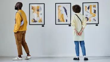 Visitors looking at paintings on a gallery wall