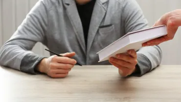 Author signing a copy of a book at a table