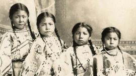 Studio portrait of four unidentified young girls, possibly members of the Crow Indian tribe.