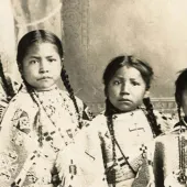 Studio portrait of four unidentified young girls, possibly members of the Crow Indian tribe.