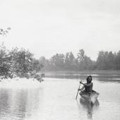 Native American man with canoe on river